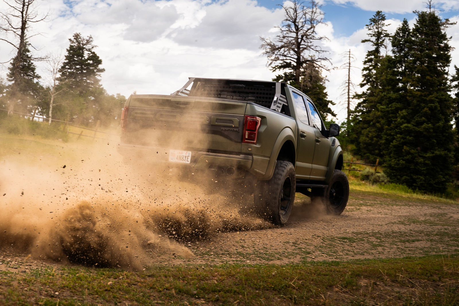A Ford Raptor with a Big Days Chase Rack System and Headache Rack going off road in the dirt