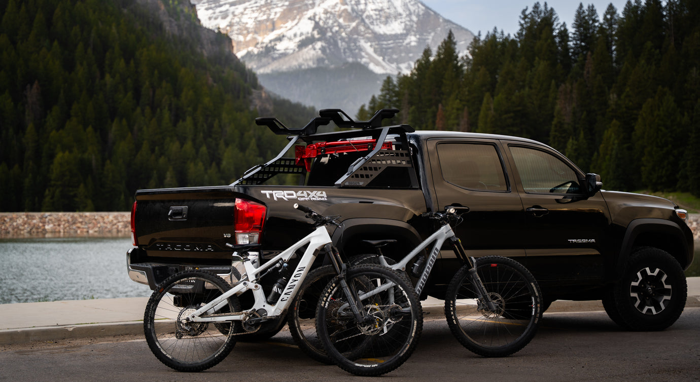 A Toyota Tacoma with a truck bed bike rack and two mountain bikes in the mountains 