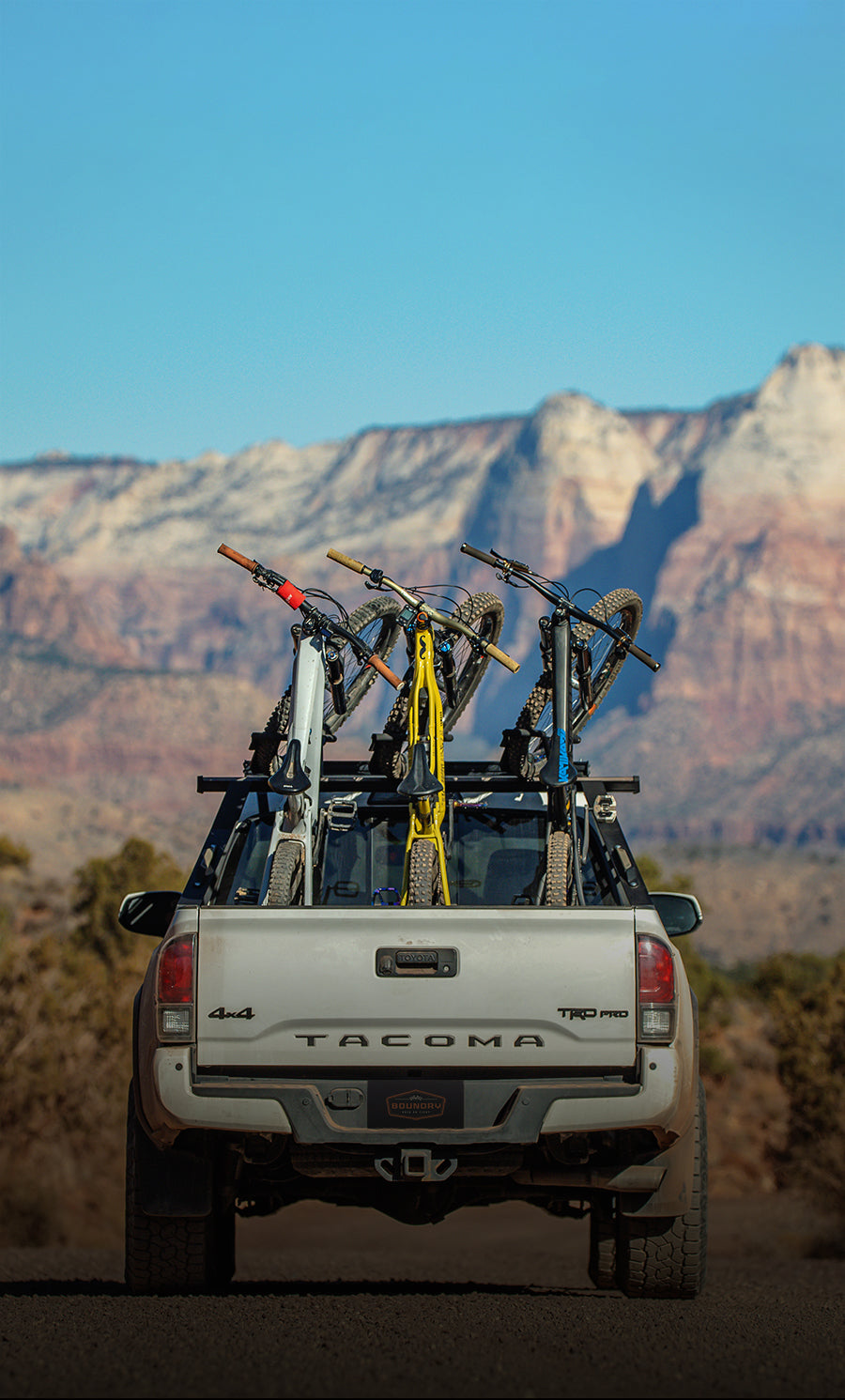 A truck bed bike rack on a Toyota Tacoma to hold mountain bikes inside the bed and tow a trailer or go off roading